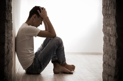 Depressionen, Junger Mann sitzt allein in einem leeren Raum und fühlt sich hoffnungslos